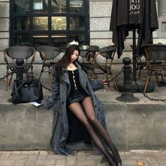 Woman in a long coat and mini skirt sitting outside a cafe