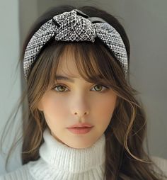 Woman with long brown hair and a headband wearing a white turtleneck sweater