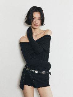 Woman with short black hair wearing an off-shoulder top and shorts