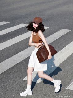 Woman in a brown crop top and white shorts crossing a street