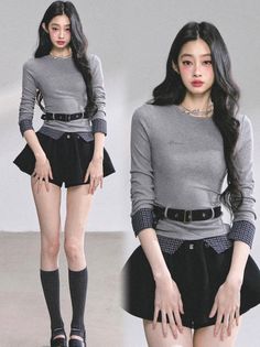 Woman with long black hair wearing a gray shirt and black mini skirt in a studio