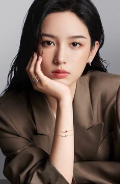 Woman with long black hair wearing a brown blazer and jewelry