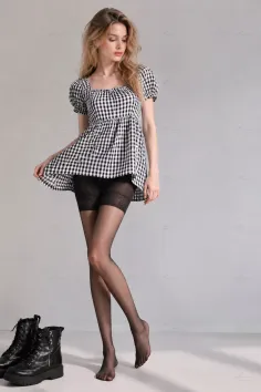 Woman in a gingham dress and black tights with boots on the floor