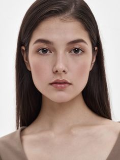 Young woman with long dark hair and natural makeup against a white background