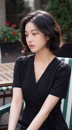 Woman with short black hair wearing a black dress outdoors