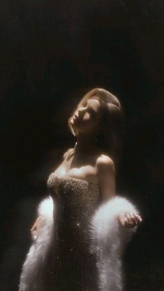 Woman in a sparkling strapless dress and white fur stole with dramatic lighting