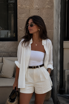 Woman in white shorts and shirt with sunglasses and jewelry outdoors
