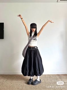 Woman in a black skirt and white top with arms raised indoors