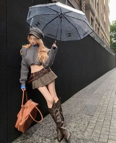 Woman in a cropped sweater and mini skirt holding an umbrella on a street