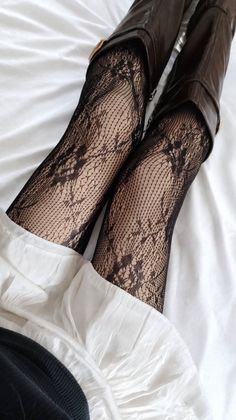 Legs wearing black lace tights and brown boots on white fabric
