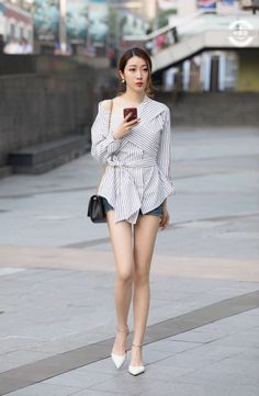 Woman in a striped shirt and denim shorts walking on a street