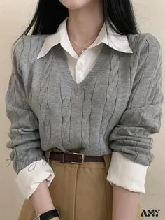 Person wearing a gray cable knit sweater over a white collared shirt with khaki pants