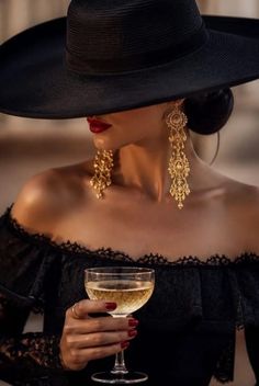 Woman in a wide brim hat and off-shoulder top holding a glass of champagne
