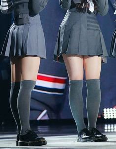 Two people in school uniforms with pleated skirts and knee-high socks on a stage