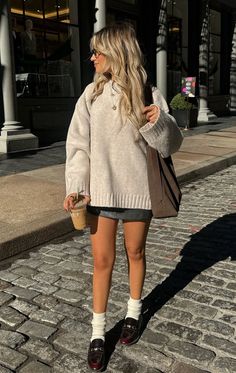 Woman in an oversized sweater and mini skirt on a cobblestone street