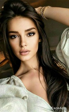 Woman with long dark hair and a gold bracelet, looking directly at the viewer