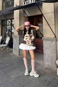 Woman in a pink bandana and graphic t-shirt with a white skirt on a city street