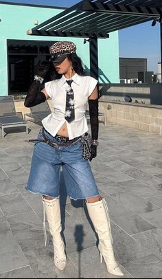 Woman in a leopard print hat, white shirt, denim shorts, and knee high boots outdoors