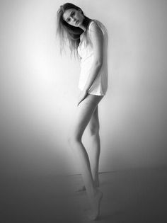 Woman in a white shirt and underwear posing against a wall