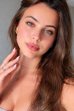 Woman with long brown hair and green eyes wearing gold jewelry