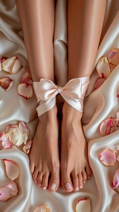 Legs and feet tied with a pink ribbon on silk fabric with rose petals