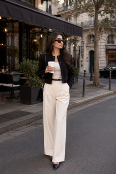 Woman in a black jacket and wide leg pants walking on a city street