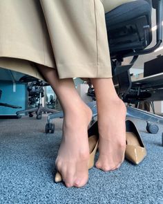 Feet in nylon socks with high heels on an office carpet