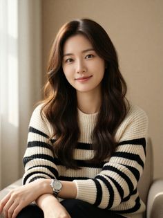 Woman with long wavy hair wearing a striped sweater indoors