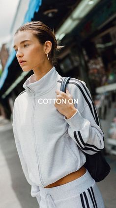 Woman in a grey tracksuit with a cropped jacket and exposed midriff on a street