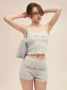 Woman in a gray ribbed tank top and shorts with a choker and glasses