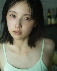 Woman with short black hair in a light green tank top indoors