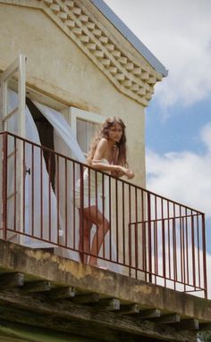 Woman with long hair in a white dress standing on a balcony