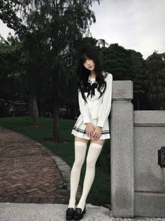 Woman in a white school uniform and thigh-high socks outdoors