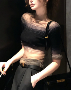 Woman in a sheer top and black pants with a shoulder bag