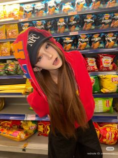 Person with long hair wearing a red hoodie and baseball cap in a supermarket aisle