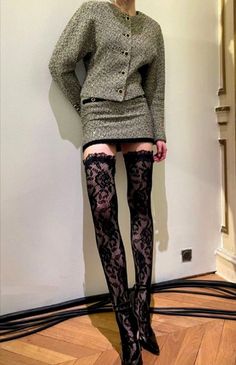 Person in a tweed suit, mini skirt, and lace stockings indoors