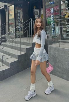 Woman in a gray crop top and mini skirt walking on a street