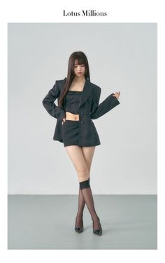 Woman in a black blazer, crop top, and mini skirt posing in a studio