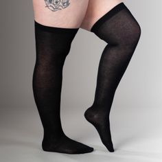 Person wearing black thigh-high stockings with a tattoo on the upper thigh