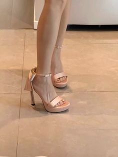 Person wearing pink high heels with bow detail and a pedicure on a tile floor