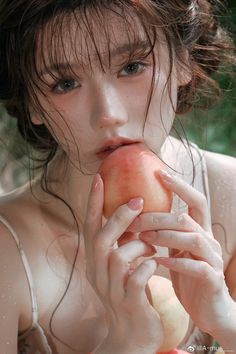 Woman with wet hair and skin holding a peach to her lips