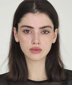 Woman with dark hair and freckles looking directly at the camera