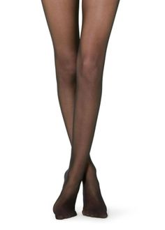 Person wearing black sheer tights with legs crossed on a white background