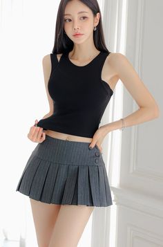 Woman in a black tank top and pleated skirt with a belly button piercing