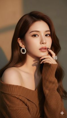 Woman with long brown hair wearing an off-shoulder brown sweater and jewelry