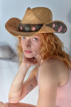 Woman with red hair and a cowboy hat looking at the camera