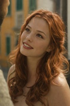Woman with red hair and freckles smiling outdoors