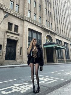 Woman in a black fur coat and leopard print top on a city street
