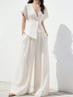 Woman in a white linen top and wide leg pants outdoors