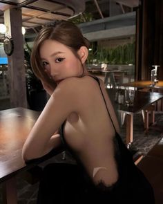 Woman in a black lace-trim dress posing suggestively indoors
